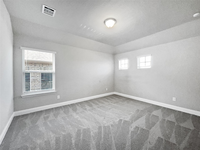 carpeted empty room featuring a textured ceiling