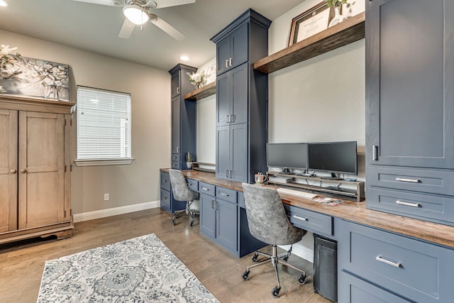 office featuring built in desk, light hardwood / wood-style floors, and ceiling fan