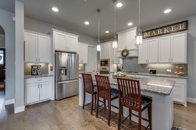 kitchen with stainless steel appliances, white cabinetry, a kitchen island, and light hardwood / wood-style flooring