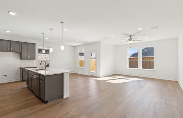 kitchen featuring sink, a kitchen island with sink, light hardwood / wood-style floors, and decorative light fixtures