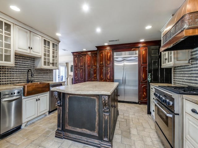 kitchen featuring tasteful backsplash, premium range hood, high end appliances, sink, and a kitchen island