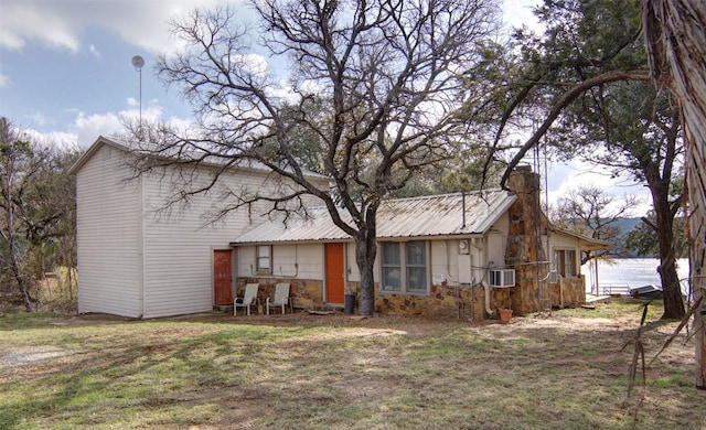 back of property with a lawn and a water view