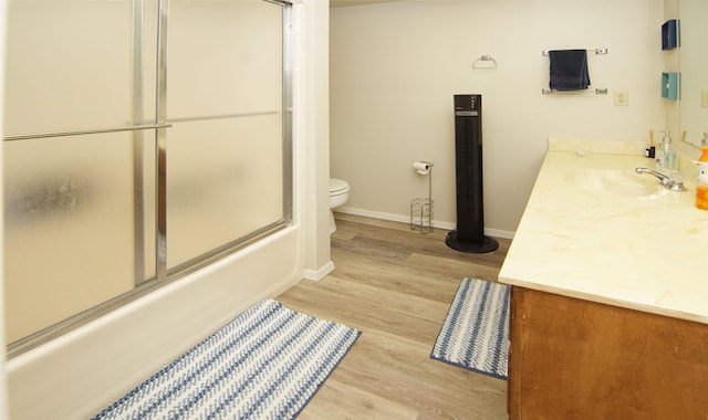 full bathroom with enclosed tub / shower combo, wood-type flooring, vanity, and toilet