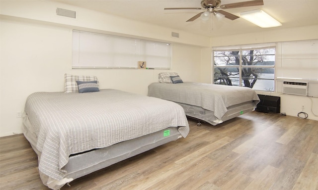 bedroom featuring hardwood / wood-style floors, ceiling fan, and cooling unit