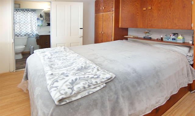 bedroom featuring sink, connected bathroom, and light hardwood / wood-style flooring