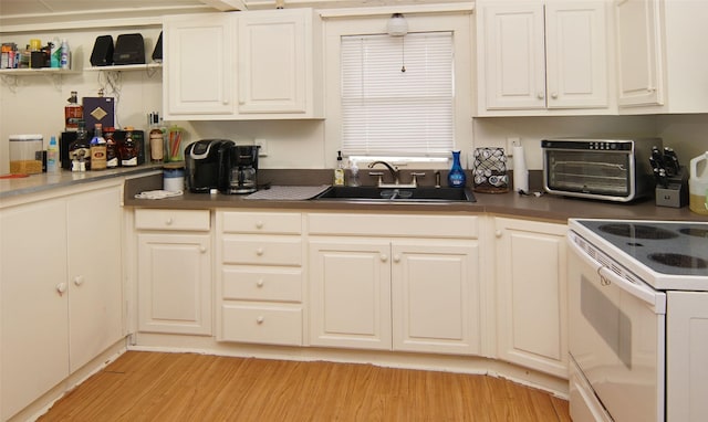 kitchen featuring light hardwood / wood-style floors, white range with electric stovetop, white cabinetry, and sink