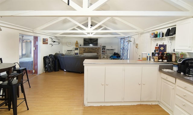 kitchen featuring vaulted ceiling with beams, white cabinets, and light hardwood / wood-style floors