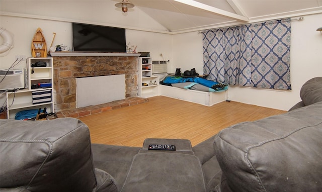 living room featuring wood-type flooring, a stone fireplace, and lofted ceiling