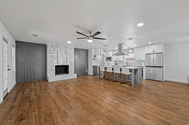 unfurnished living room featuring ceiling fan, a high end fireplace, and light hardwood / wood-style floors