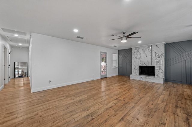 unfurnished living room with a premium fireplace, ceiling fan, and light hardwood / wood-style floors