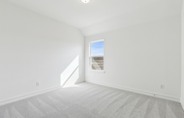 carpeted spare room featuring vaulted ceiling