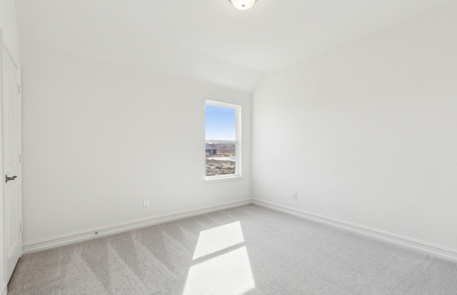 carpeted empty room with vaulted ceiling