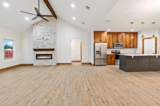 kitchen with stainless steel appliances, tasteful backsplash, light hardwood / wood-style floors, decorative light fixtures, and a fireplace