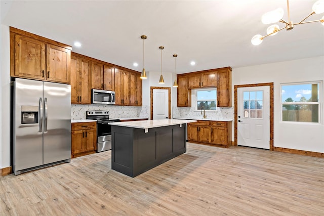 kitchen with a kitchen island, pendant lighting, light wood-type flooring, and appliances with stainless steel finishes