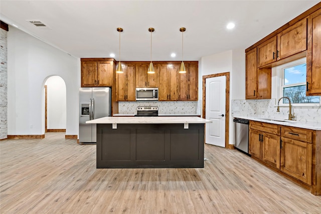 kitchen with appliances with stainless steel finishes, a center island, hanging light fixtures, and sink