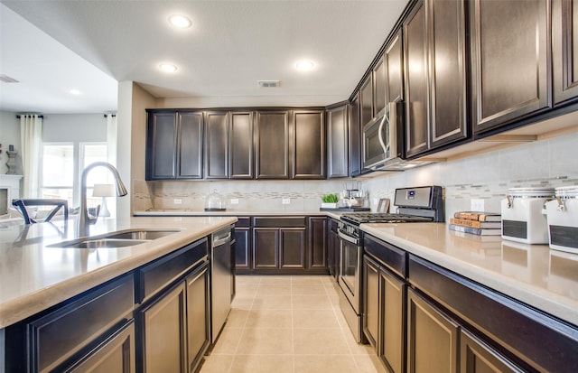 kitchen featuring sink, light tile patterned floors, appliances with stainless steel finishes, dark brown cabinets, and decorative backsplash