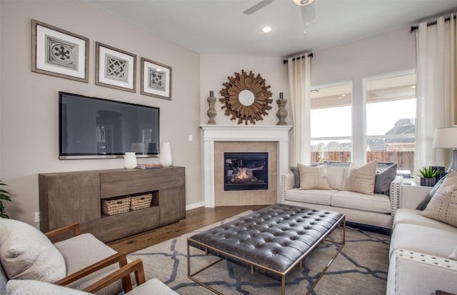 living room featuring hardwood / wood-style flooring, a tiled fireplace, and ceiling fan