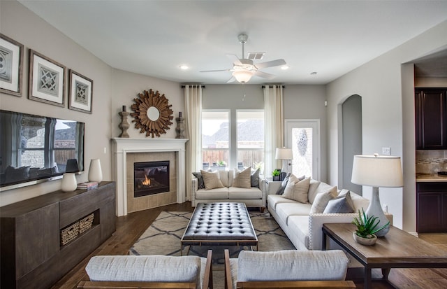 living room with a fireplace, dark wood-type flooring, and ceiling fan