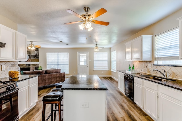 kitchen with black appliances, white cabinets, sink, decorative backsplash, and a kitchen island