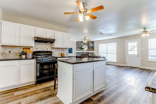 kitchen featuring tasteful backsplash, black range with gas cooktop, light hardwood / wood-style floors, white cabinets, and custom exhaust hood