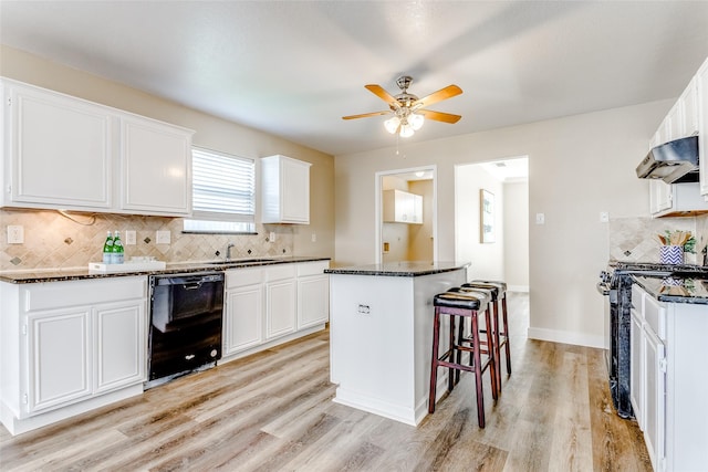 kitchen with black appliances, a center island, and white cabinets