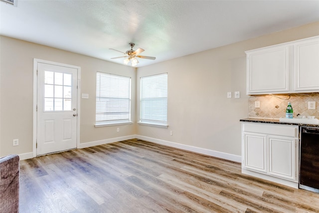 interior space with white cabinets, decorative backsplash, light hardwood / wood-style floors, and ceiling fan