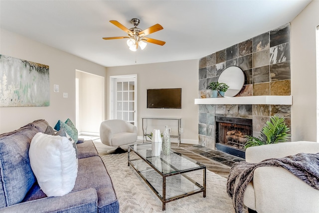 living room featuring a tiled fireplace and ceiling fan