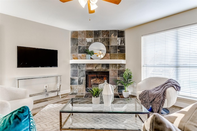 living room with a tiled fireplace, ceiling fan, and hardwood / wood-style flooring