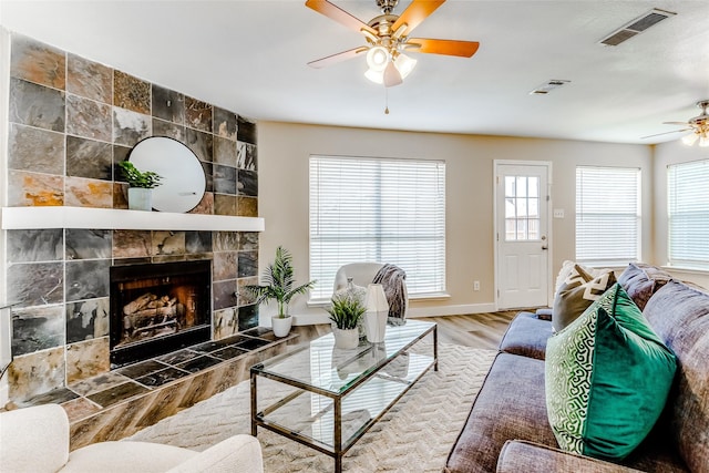 living room with a fireplace, wood-type flooring, and ceiling fan