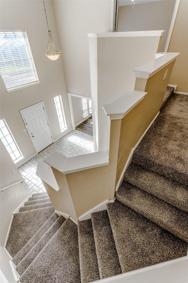 stairs featuring carpet flooring, a towering ceiling, and a wealth of natural light