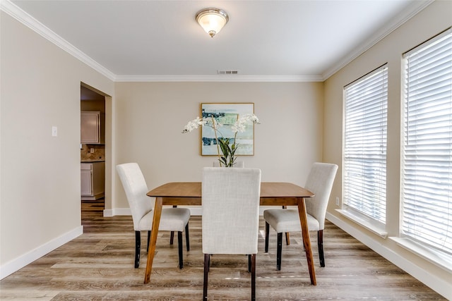 dining room with hardwood / wood-style floors, plenty of natural light, and ornamental molding