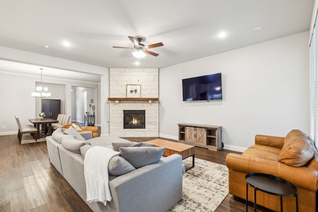 living room featuring dark hardwood / wood-style floors, a fireplace, and ceiling fan with notable chandelier