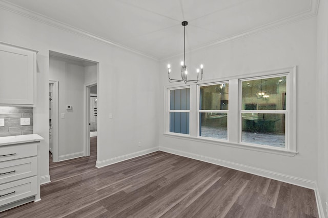 unfurnished dining area featuring dark hardwood / wood-style flooring, ornamental molding, and a chandelier