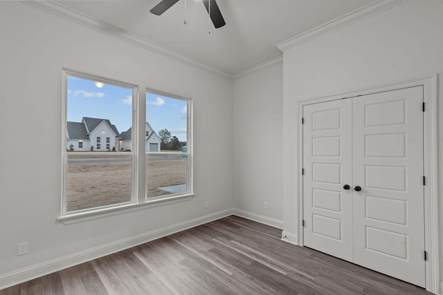 unfurnished bedroom featuring crown molding, wood-type flooring, a closet, and ceiling fan