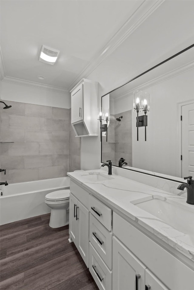 full bathroom featuring crown molding, hardwood / wood-style flooring, vanity, tiled shower / bath, and toilet