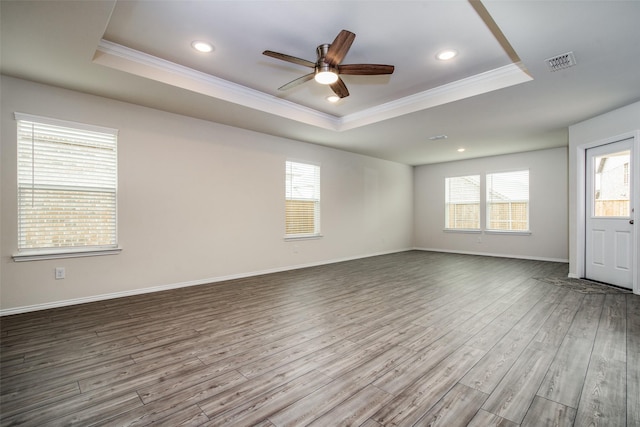 empty room featuring a raised ceiling, ceiling fan, crown molding, and hardwood / wood-style flooring