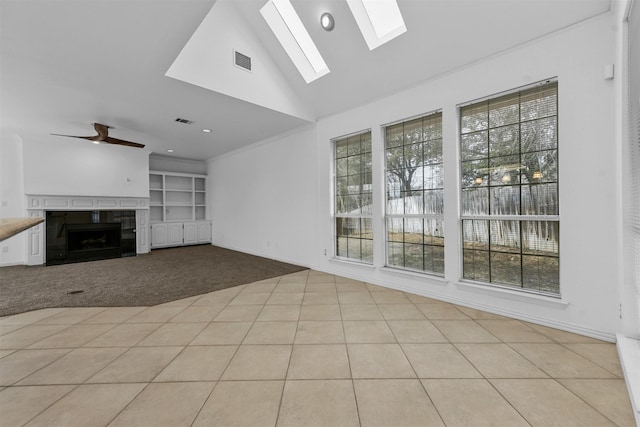 unfurnished living room with a tile fireplace, plenty of natural light, built in features, and ceiling fan