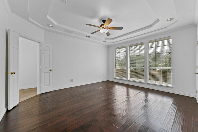 empty room featuring dark wood-type flooring, ceiling fan, ornamental molding, and a raised ceiling