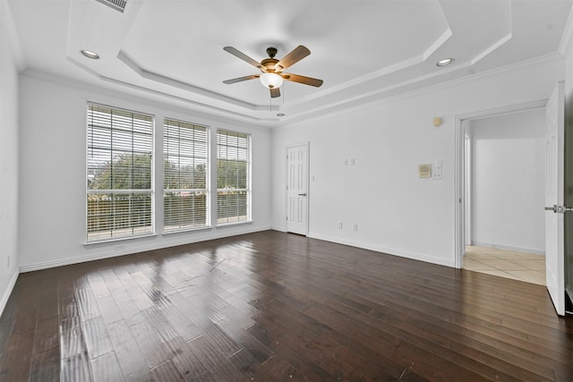 spare room featuring dark hardwood / wood-style flooring, ornamental molding, a raised ceiling, and ceiling fan