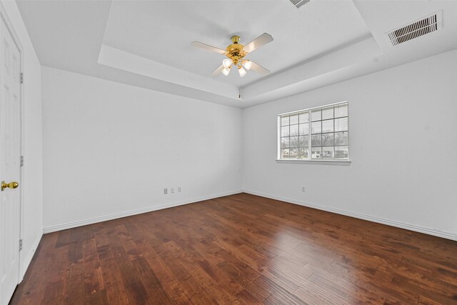 spare room featuring a tray ceiling, dark wood-type flooring, and ceiling fan