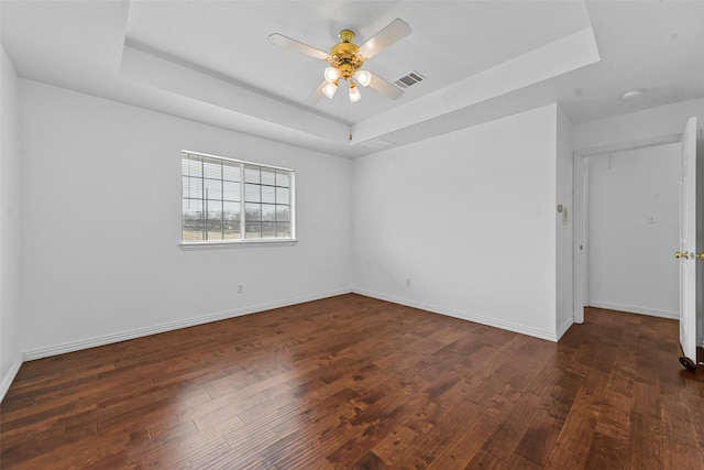 unfurnished room featuring ceiling fan, dark hardwood / wood-style flooring, and a raised ceiling