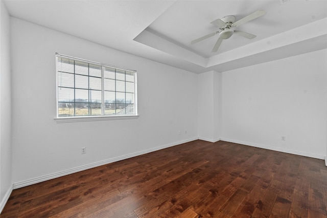 spare room featuring dark wood-type flooring, ceiling fan, and a tray ceiling