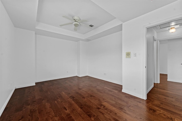 unfurnished room with a raised ceiling, dark hardwood / wood-style floors, and ceiling fan