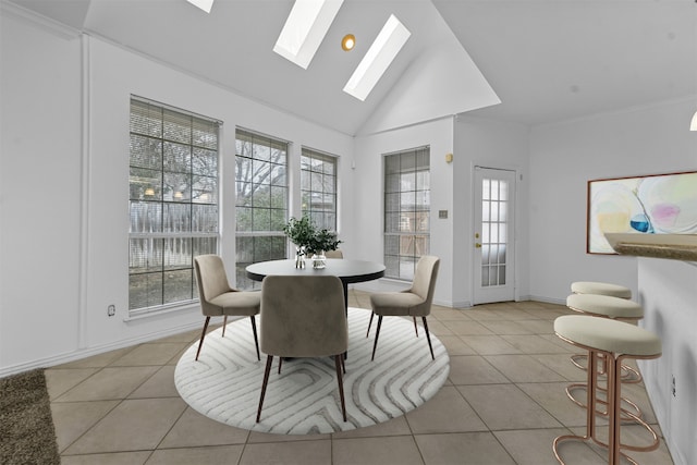 dining room with light tile patterned flooring, a wealth of natural light, high vaulted ceiling, and a skylight