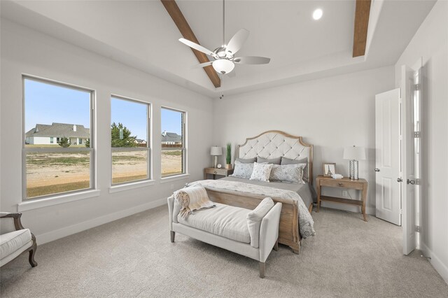bedroom with a tray ceiling, light colored carpet, baseboards, and a ceiling fan
