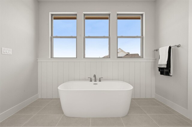 bathroom with tile patterned flooring, plenty of natural light, and a freestanding bath