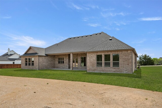 back of property featuring fence, a patio, brick siding, a lawn, and a shingled roof