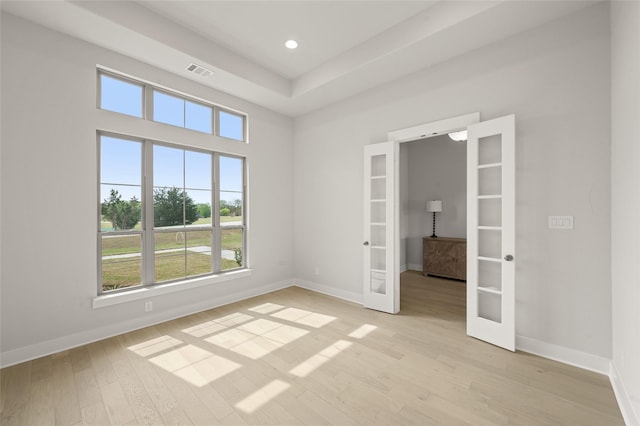 empty room featuring baseboards, light wood-style flooring, visible vents, and french doors