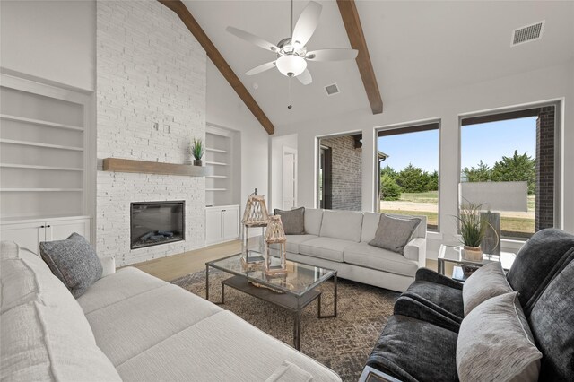 living area featuring visible vents, built in shelves, wood finished floors, a ceiling fan, and beam ceiling
