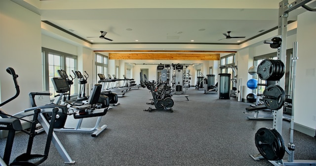 exercise room with ceiling fan and a tray ceiling